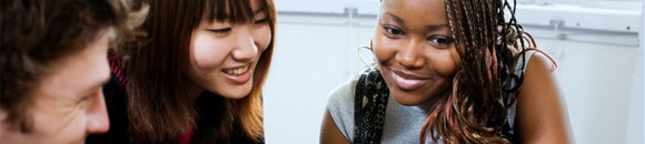 Image of two female students sitting at a desk and looking at the same study book